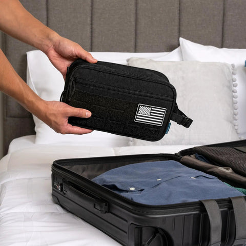 Person packing Tactical Toiletry Bag For Men Water Resistant Military Molle Dopp Kit Travel Organizer into suitcase on bed