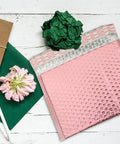 Pink 25 Pack Self Seal Bubble Mailer Envelopes 25x20cm on wooden table with green paper and flower