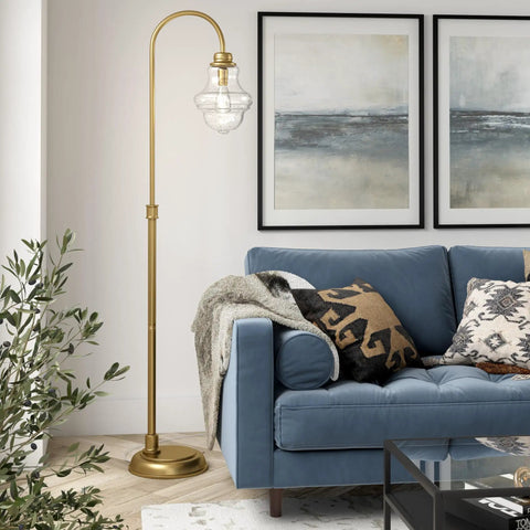 70 Inch Tall Arc Floor Lamp With Teardrop Seeded Glass Shade In Brass Finish beside blue sofa in living room