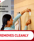 Person removing X Large Satin Nickel Triple Hook with adhesive strips from wooden wall using 3M stretch release technology