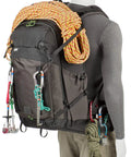 Mannequin carrying BackLight 36L Outdoor Adventure Camera Daypack Backpack In Woodland Green with climbing gear attached