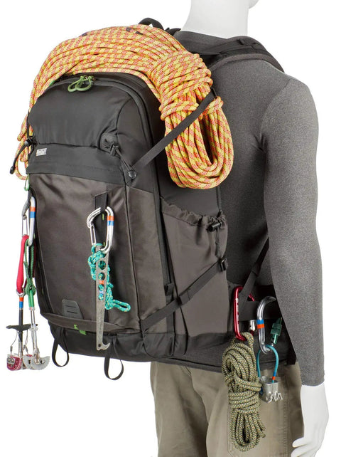 Mannequin carrying BackLight 36L Outdoor Adventure Camera Daypack Backpack In Woodland Green with climbing gear attached