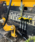 LockNLube grease fitting caps, red, 50-count, mounted on a four-port block with hoses on yellow equipment
