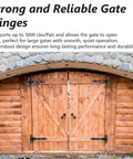 Two black heavy-duty gate hinges mounted on wooden double doors.