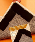Non Slip Rug Grippers Set, Reusable Double Sided Carpet Tape Pads With Super Strong Adhesive For Area Rugs shown under a rug corner