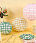 12 Pack Camp Bachelorette Paper Lanterns Set in Gingham Green Tan Pink displayed with floral decor on a table