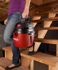 Person carrying 1.5 Gallon 2.0 Peak Wet Dry Vacuum For Quick Cleanups At Home, Garage, Or Vehicle, with collapsible handle.