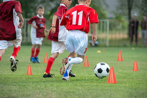Children playing soccer among 15 Inch Orange Traffic Safety Cones 7 Pack High Visibility Pro Grade Durable Plastic Parking And Training Cones
