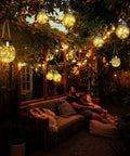 Outdoor evening scene with glowing 2 Pack Solar Lanterns With 30 LED Waterproof Garden Lights For Patio Hanging, warm white glow.