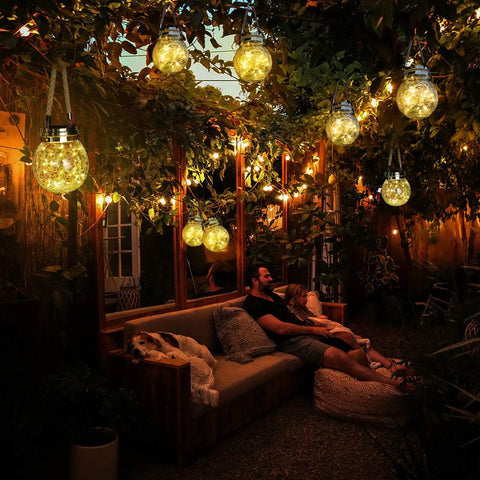 Outdoor evening scene with glowing 2 Pack Solar Lanterns With 30 LED Waterproof Garden Lights For Patio Hanging, warm white glow.