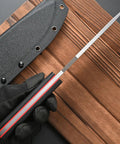 Close-up of the Rugged AUS 10 Fixed Blade Knife with Carbon Fiber Handle showing full tang blade and sheath on wood surface.