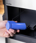 Person holding a blue filter for the Genuine Game Changing Nugget Ice Maker With Smart Wifi App And Built In Scale Fighting Filter Makes Hella Crisp Chewable Pellet Ice Fast Comes With Handy Scoop Sleek Stainless Build.