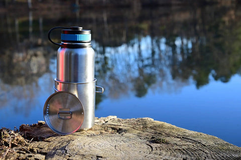 Stainless Steel Canteen Water Bottle with Nested Camping Cup and Lid by riverside on wooden stump