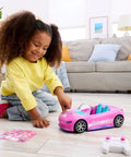 Child playing with Remote Control Pink Convertible RC Toy Car With Dual Driving Modes, toy car and remote on the floor.