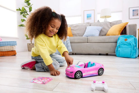 Child playing with Remote Control Pink Convertible RC Toy Car With Dual Driving Modes, toy car and remote on the floor.