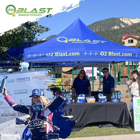 Outdoor event booth displaying 99.99 Percent Pure Oxygen On The Go Can With Mask, with staff and promotional setup.