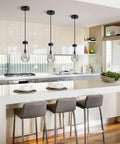Modern kitchen with gray bar stools and pendant lights above island, featuring a sleek, minimalist design.