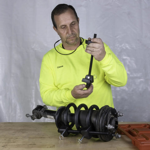 Man using MacPherson Strut Coil Spring Compressor Tool for safe and easy spring compression, shown on a workbench.