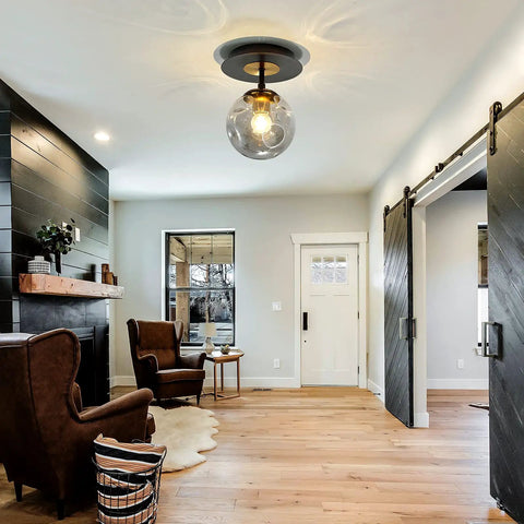 Sleek 1 Light Mini Glass Globe Ceiling Light In Black Finish Semi Flush Mount illuminating a modern living room.