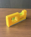 QERDIVO Spirit Levels Mini Horizontal Vertical Pockets Spirit Levels Spirit Bubble Leveler in bright yellow design on wood surface.