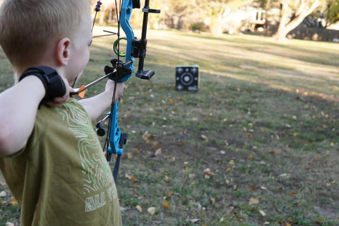 Child aiming a bow at Travel Pro Portable Layered Foam Archery Target With Welded Core Technology in a backyard