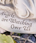 Close-up of 'Angels are Watching Over Us' engraving on solar garden light base, part of Watching Over Us Praying Angel Solar Garden Light LED Outdoor Decor For Home Patio And Yard, Angel Statue For Lawn Pathway Or Porch, Solar Powered Yard Art With Cozy Glow And Good Vibes, Blessings Hope And Comfort.