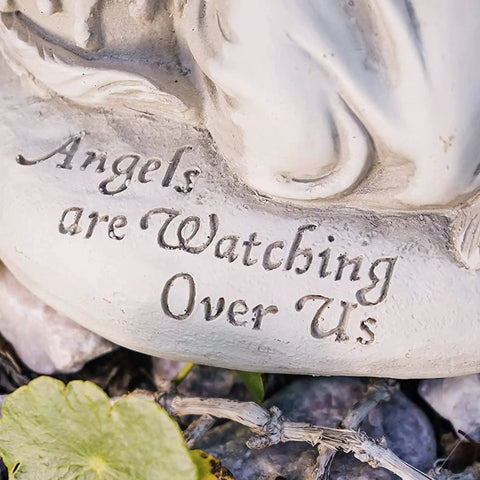 Close-up of 'Angels are Watching Over Us' engraving on solar garden light base, part of Watching Over Us Praying Angel Solar Garden Light LED Outdoor Decor For Home Patio And Yard, Angel Statue For Lawn Pathway Or Porch, Solar Powered Yard Art With Cozy Glow And Good Vibes, Blessings Hope And Comfort.