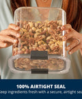 Woman holding Straight Up 12 Cup Airtight Food Storage Container with nuts inside, showcasing secure snap lid and clear design.