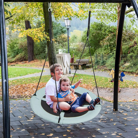 Kids playing on 40 Inch Saucer Tree Swing For Kids With Carabiners, Adjustable Hanging Ropes From 55 To 71 Inches, in a green forest