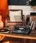 Front view of Audio-Technica at-LPGO-BT turntable, gun-metal/black with clear dust cover, playing vinyl on a coffee table