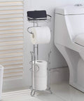 Free Standing Chrome Toilet Paper Holder With Reserve Shelf And Storage Basket next to toilet, holding three mega rolls