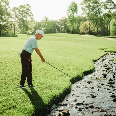 Golfer retrieving ball from water with Jawz Golf Ball Retriever With 14 Foot Length And 18 Foot Reach, Ultra Compact Design