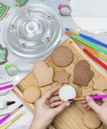 Top Tier Knockout 56 Piece Cookie Decorating Kit With Solid Acrylic Turntable Non Slip Pad Premium Piping Bags Stainless Icing Tips And Dope Brushes For Sweet Kitchen Creations shown with cookies and brushes.