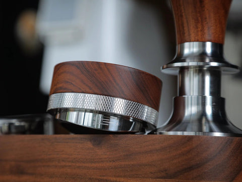 Close-up of KNODOS 54mm espresso distribution tool with rosewood handle and knurled stainless steel ring