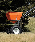 Heavy Duty 70 Pound Spreader With Stainless Steel Frame For All Flowable Materials Delivers Precise Pattern And Accuracy Reinforced Frame With Larger Axle And 13 Inch Tires Rugged Gearbox Extended Handle Front Hopper Guard For Safety shown in use on lawn