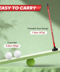 Red magnetic golf alignment rod and two golf balls displayed on a balance scale highlighting portable design and weight.