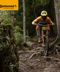 Mountain biker in orange gear riding through a forest trail