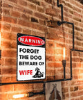 Hella Durable Metal Wall Art Sign For The Man Cave Featuring Funny Forget The Dog Beware Of Wife Quote In Rust Proof Aluminum Garage Decor That Is Legit Tough And Totally Bro Approved 12 By 8 Inch on a brick wall.