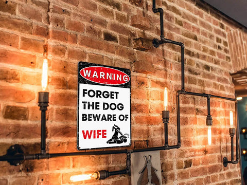 Hella Durable Metal Wall Art Sign For The Man Cave Featuring Funny Forget The Dog Beware Of Wife Quote In Rust Proof Aluminum Garage Decor That Is Legit Tough And Totally Bro Approved 12 By 8 Inch on a brick wall.