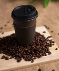 16 Oz Disposable Coffee Cups With Lids And Sleeves Pack Of 100 Brown And Black Insulated To Go Cups surrounded by coffee beans.