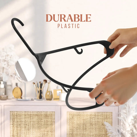 Hands holding a black plastic hanger from the 50 Pack Black Plastic Clothes Hangers For Closet Organization And Space Saving.