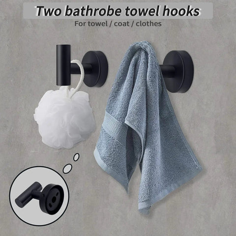 Six Piece Matte Black Bathroom Hardware Set With 16 Inch Hand Towel Bar Toilet Paper Holder Two Wall Towel Hooks And Two Robe Hooks Modern Wall Mounted Stainless Steel Bath Accessories For A Sleek Durable Dope Look showing two black wall-mounted hooks holding towel and loofah.
