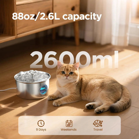 Cat lying next to Stainless Steel Cat Water Fountain Two Point Six Liter Ultra Quiet Pet Fountain With Flower Spout And LED Blue Light Water Dispenser Water Level Window Indoor Use For Cats And Dogs Silver Finish, showing 2600ml capacity.
