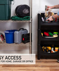 Person using Jumbo Stackable Storage Bins Pack Of 3 With Large Easy Grip Handles And Wide Front Opening For Quick Access Interlocking And Vertical Stacking Heavy Duty Rust And Water Resistant Black in garage