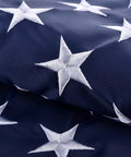 Close-up of white embroidered stars on blue fabric, part of 5x8 Ft US Flag For Outdoor Use High Wind With Embroidered Stars And Sewn Stripes Brass Grommets Built To Last In Any Weather UV Protected Water Resistant Weatherproof Durable Outdoor Flag.