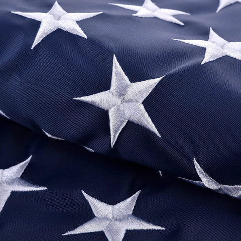 Close-up of white embroidered stars on blue fabric, part of 5x8 Ft US Flag For Outdoor Use High Wind With Embroidered Stars And Sewn Stripes Brass Grommets Built To Last In Any Weather UV Protected Water Resistant Weatherproof Durable Outdoor Flag.