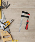 Heavy Duty Metal F Clamps For Welding And Woodworking With 6 Inch Opening in a workspace surrounded by tools.