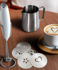 Complete Home Coffee Frother Set With Upgraded Ultra Stand Barista Grade Handheld Milk Foam Maker Mini Blender Whisk Frothing Pitcher Stencils And More Perfect Gift For Lattes Cappuccinos Mochas And Matcha At Home with stainless steel pitcher, foam maker, and latte stencils on a table.
