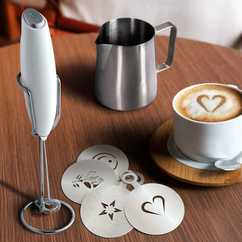 Complete Home Coffee Frother Set With Upgraded Ultra Stand Barista Grade Handheld Milk Foam Maker Mini Blender Whisk Frothing Pitcher Stencils And More Perfect Gift For Lattes Cappuccinos Mochas And Matcha At Home with stainless steel pitcher, foam maker, and latte stencils on a table.