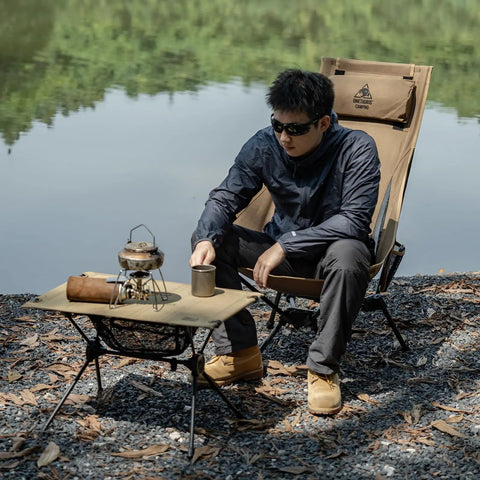 Man sitting by lake in a Tigerblade High Back Camping Chair With Pillow Design Ultra Comfy Widened Seat Foldable Outdoor Chair